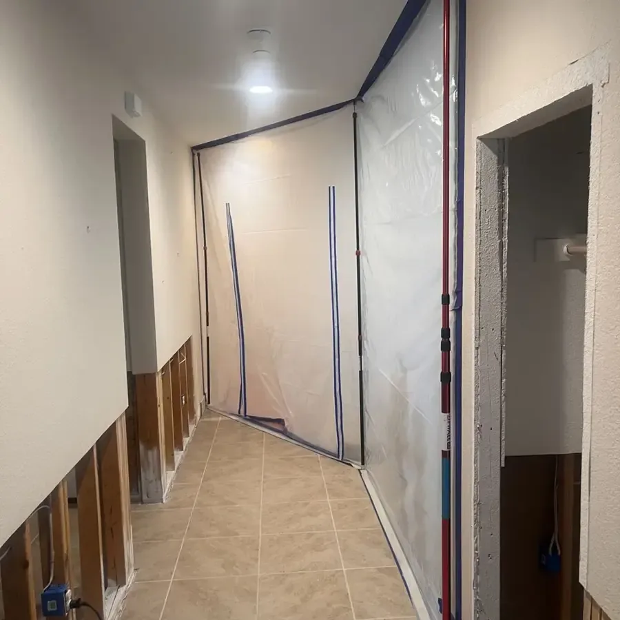 Open wall bases and protective sheeting along a tiled hallway