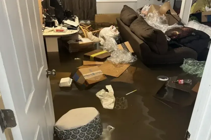 Standing water surrounds furniture and belongings in a living room