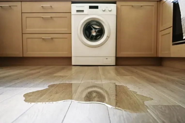Water leaking from a washing machine across a kitchen floor